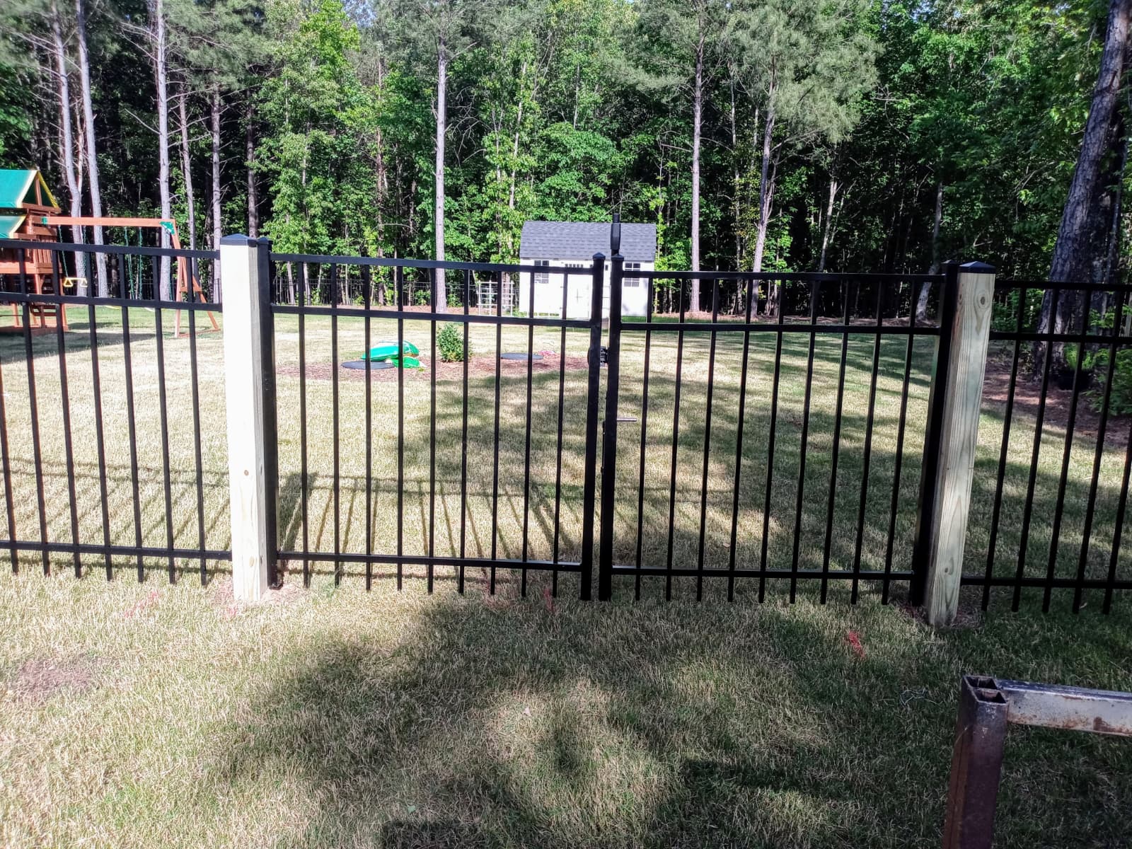 Black aluminum fence installation around a residential yard