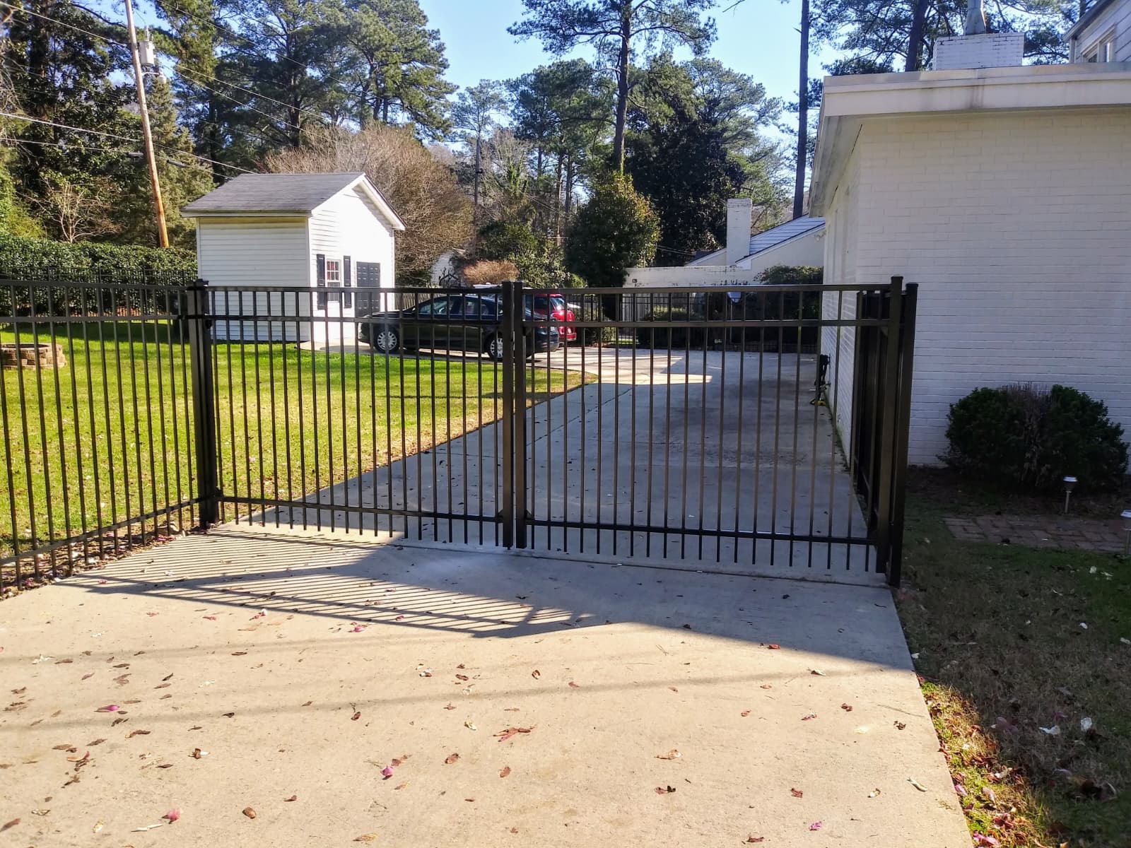 Black aluminum driveway gate and fence installation